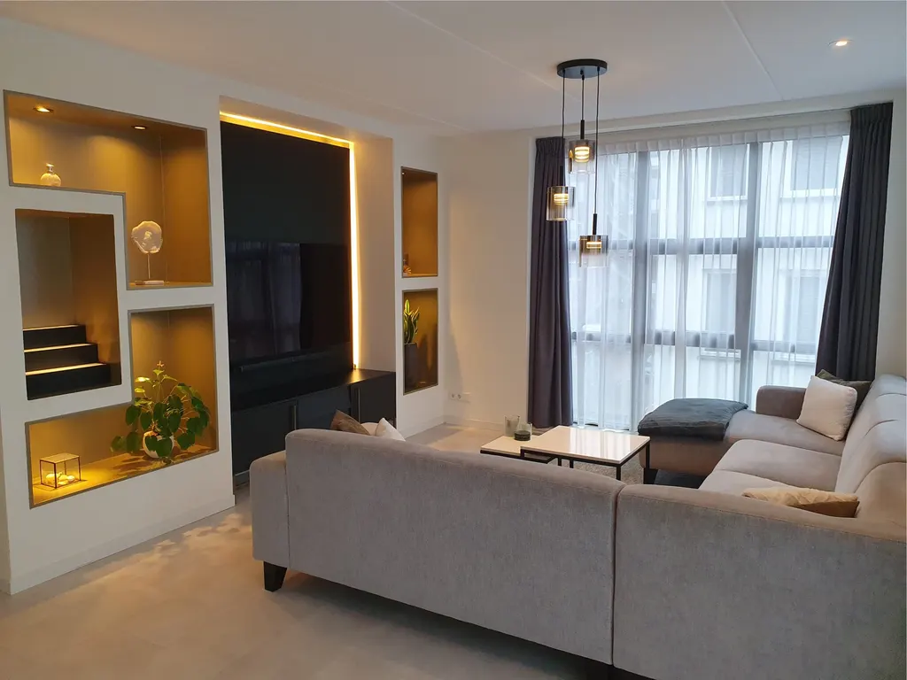 Woonkamer van een appartement in Almere Poort met verlichte nissen, tv-wand en hoekbank