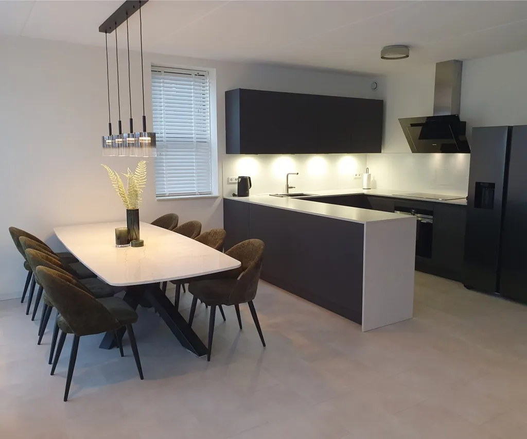 Open keuken met donkere keukenkasten, eettafel en hanglamp