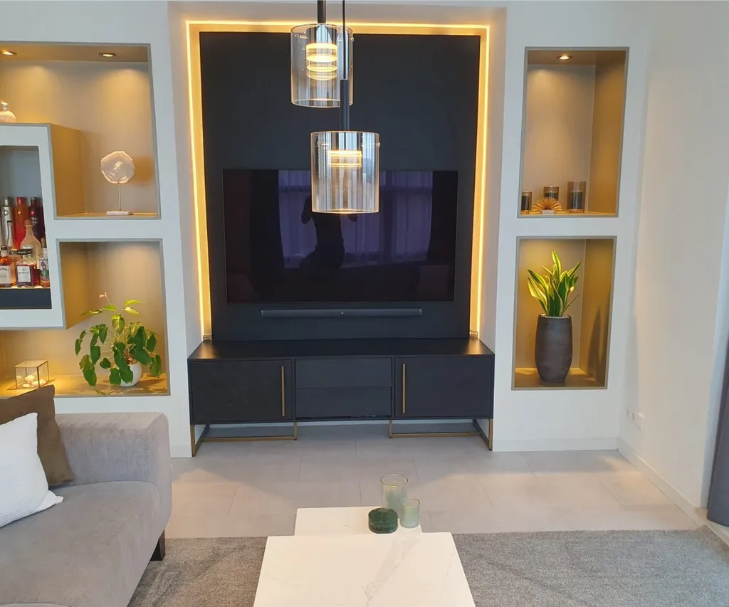 Tv-wand met verlichte nissen en een zwart tv-meubel